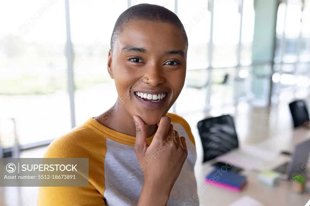 Portrait of smiling african american businesswoman with short hair in creative office. creative business and office workplace.