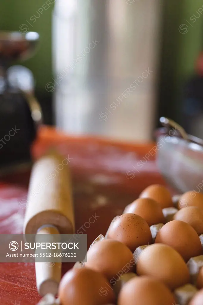 Close-up of brown eggs on carton by rolling pin on wooden table at home. organic and healthy eating.