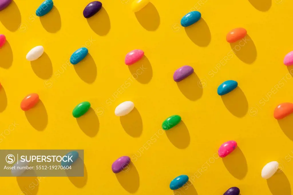 Full frame shot of multi colored candies arranged in a row on yellow background. unaltered, sweet food and unhealthy eating concept.