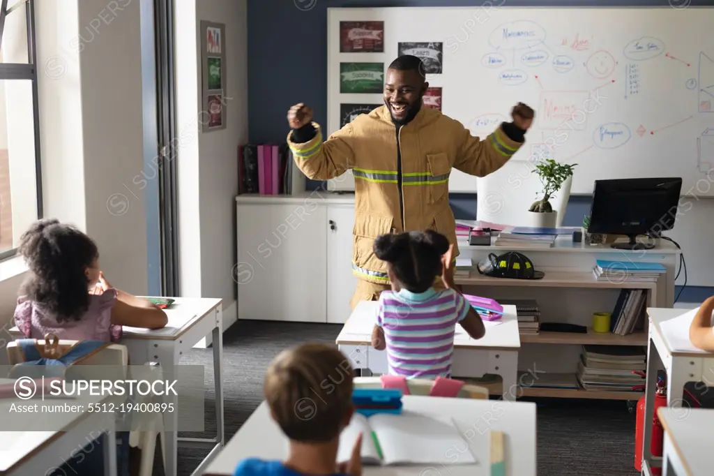 African american young male teacher in firefighter uniform with multiracial elementary students. unaltered, education, firefighter, safety, protection, teaching and school concept.