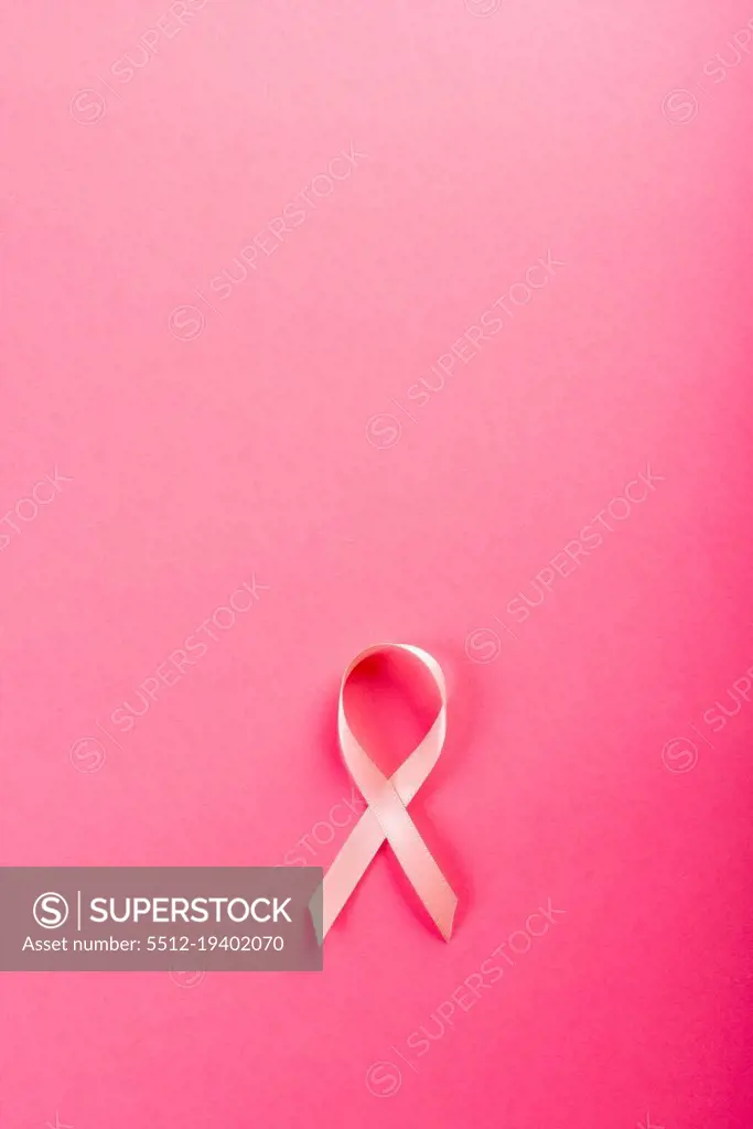 Overhead view of pink breast cancer awareness ribbon isolated against pink background. copy space. pink, breast, cancer, medical, ribbon, awareness, support, healthcare and alertness concept.