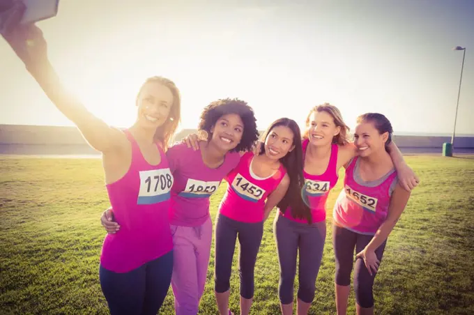 Runners supporting breast cancer marathon and taking selfies in parkland