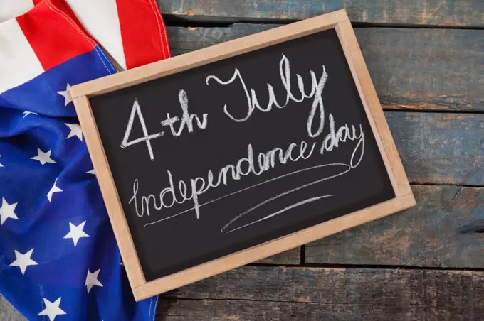 Close-up of American flag and slate with text 4th july independence day