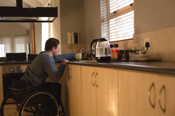 Disabled man preparing coffee in kitchen at home