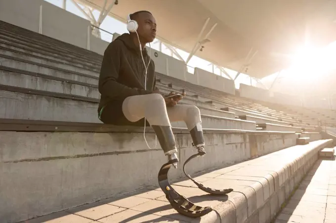 Disabled athletic listening music on mobile phone at sports venue