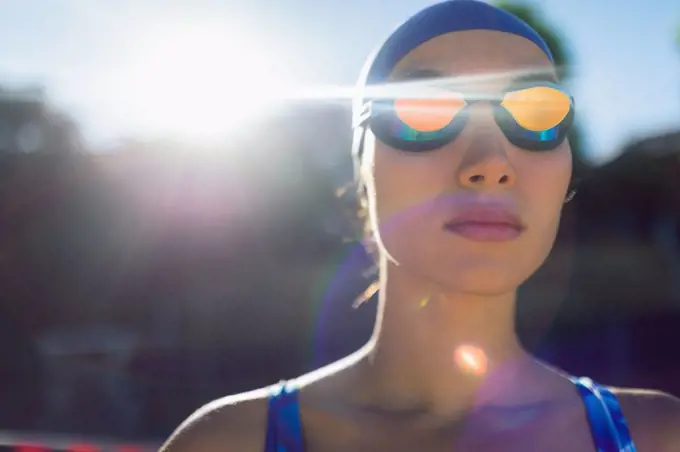 Front view of a female swimmer with swim goggles looking away in swimming pool on a sunny day