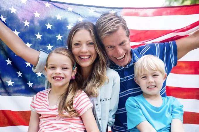 Happy family holding american flag in the park on a sunny day