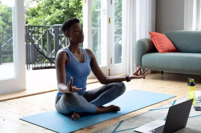 African american woman practicing yoga at home. staying at home in self isolation in quarantine lockdown