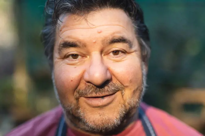 Portrait of happy caucasian male gardener looking at camera at garden centre. specialist working at bonsai plant nursery, independent horticulture business.