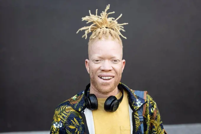 Portrait of albino african american man with dreadlocks looking at camera. on the go, out and about in the city.