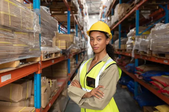 Portrait of female worker standing with arms crossed in warehouse. This is a freight transportation and distribution warehouse. Industrial and industrial workers concept