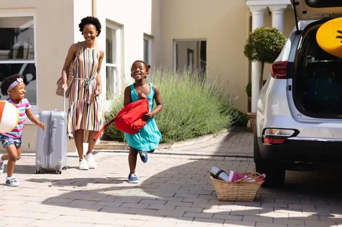 African american mother and her daughters walking towards their car outdoors. family trip and vacation concept, unaltered.