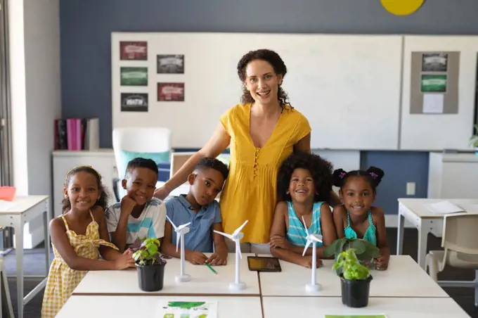 Portrait of happy african american students with caucasian young female teacher with windmill models. unaltered, education, environment, teaching, sustainable lifestyle and school concept.