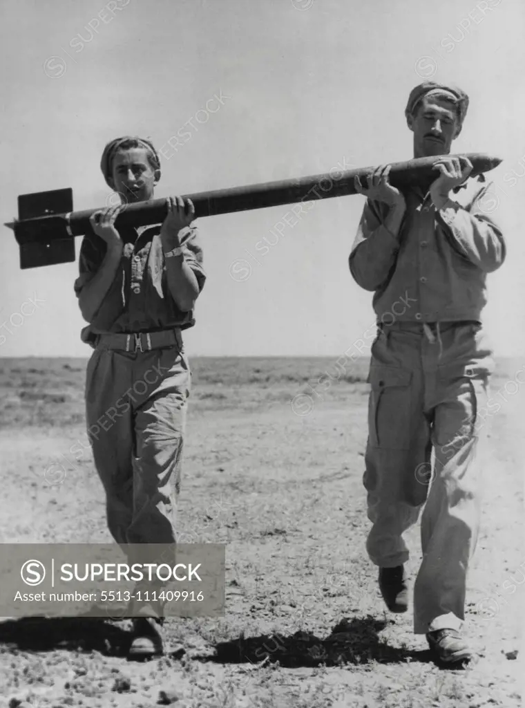 Service personnel carry rockets from jeep to launching platform. November 16, 1949.
