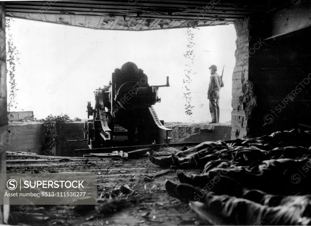 A Crack in the West Wall: A view from the interior of a large German coast defense gun with its dead crew. They and the gun were knocked out by artillery fire and naval guns during the American advance across the Cherbourg Peninsula. August 1, 1945. (Photo by Associated Press Photo).