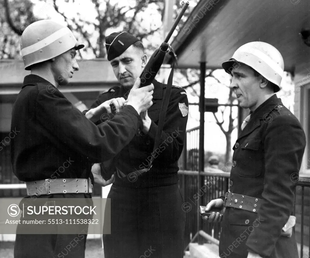 German G.I.'s (Third of Six) - Inspection time at a labor service unit barracks finds a German first Lieutenant (center) checking the rifle of a German guard under his command. November 3, 1950. (Photo by ACME).