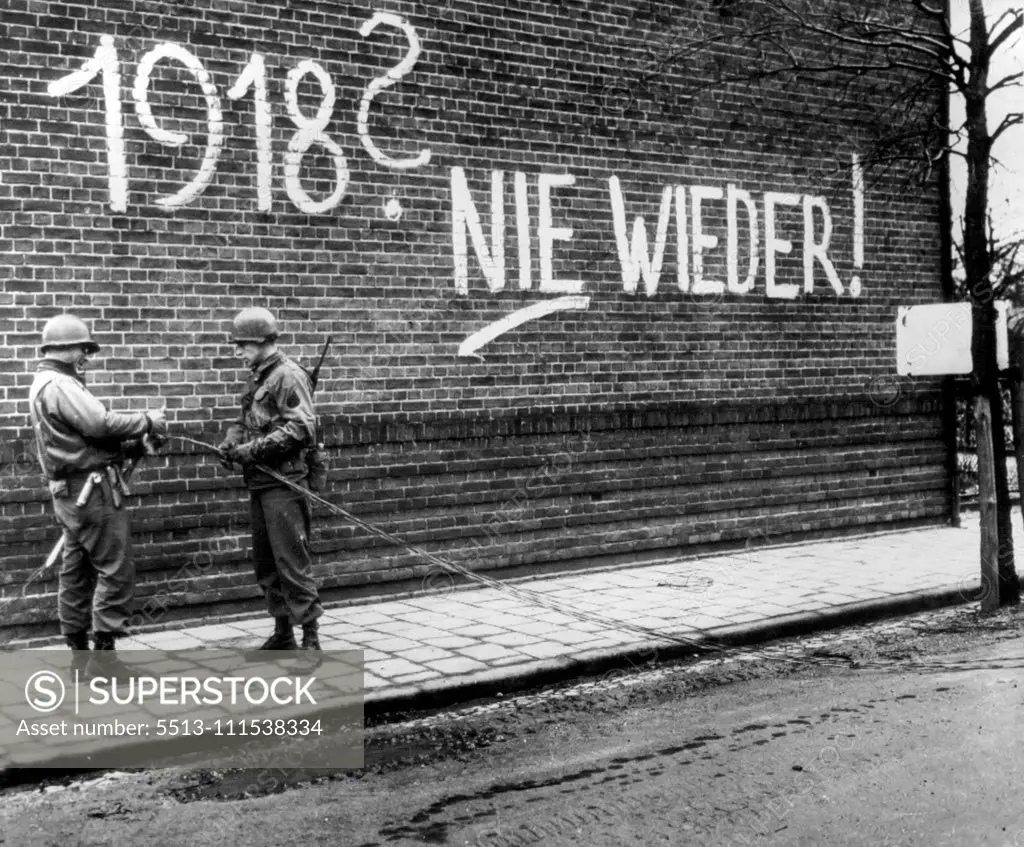 "1918 Never Again" - Two U.S. ninth army signalmen repair wires at a street corner in Echt, Holland, beside a building bearing a painted German propaganda message, reading, "1918 never again!". March 5, 1945. (Photo by AP Wirephoto).