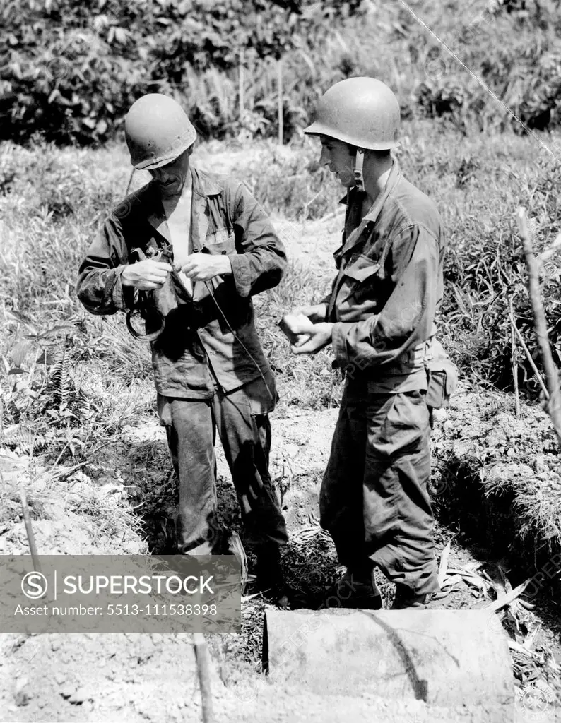 They Make A Jap Mine Innocuous - A heavy Jap mine, left ***** bridge to delay advance of the 1st Cavalry troops upon town of Infanta, Luzon Island, is prepared for destruction by soldiers who moved the mine away from bridge. Here the two soldiers - ***** Route 3, Monkers, Ohio, and John Fadorsen, ***** set booster charge to detonate the mine. May 31, 1945. (Photo by US Signal Corps.).