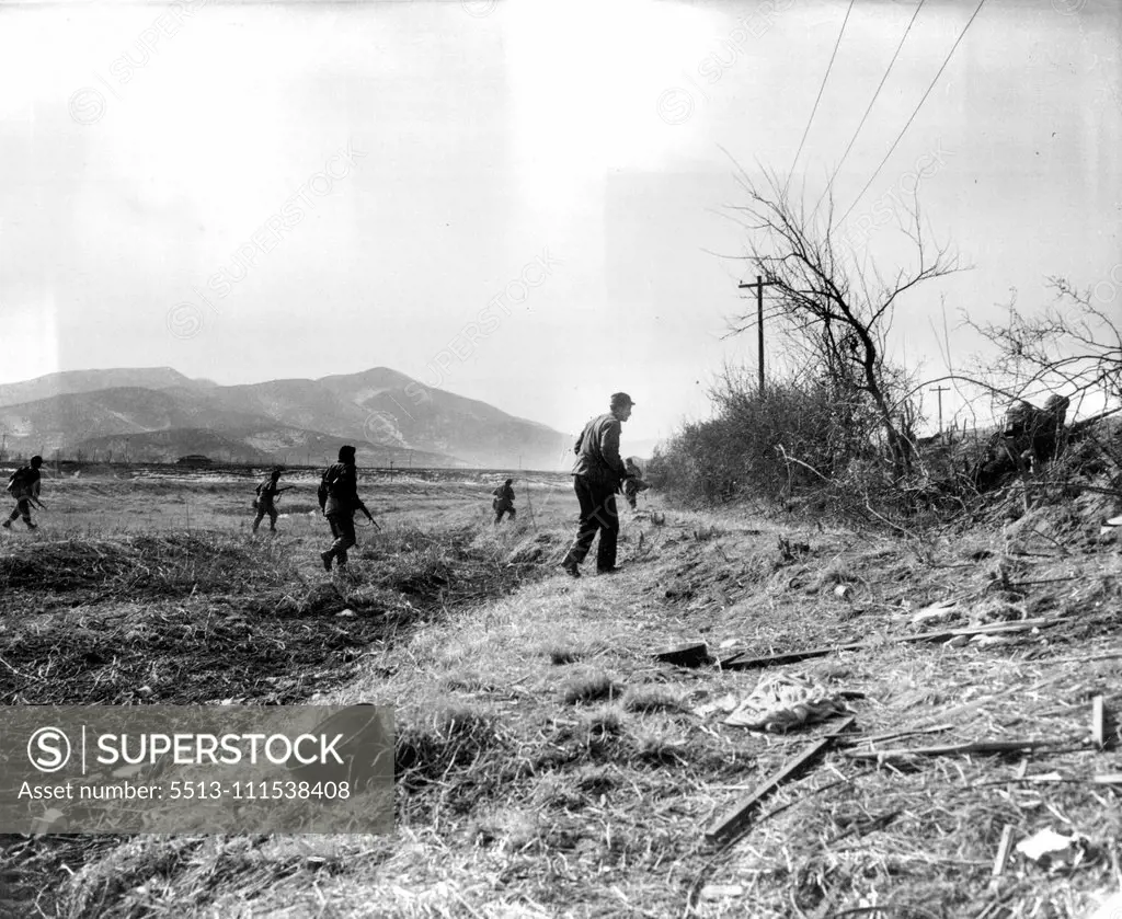A Day with the 25th (Sixth of Ten) - Moving along the front across an open field from one point of cover to another, a patrol goes quickly but cautiously for the enemy might still be lurking in the bushes. February 3, 1951. (Photo by ACME).