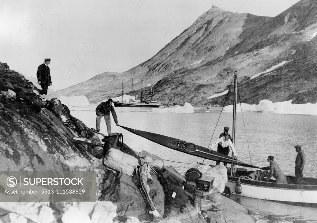 Greenland Air Survey Expedition - Watkins Last Day: Mr. H. G. Watkins, the late leader of the Greenland Artic Air Route Survey Party, who was drowned through a mishap to a kayak (Eskimo Canoe), is shown in our picture helping to unload a kayak at the Base, on the day of the Tragedy. He lost his life while seal hunting. November 21, 1932. (Photo by British Arctic Air Route Expedition Photograph).