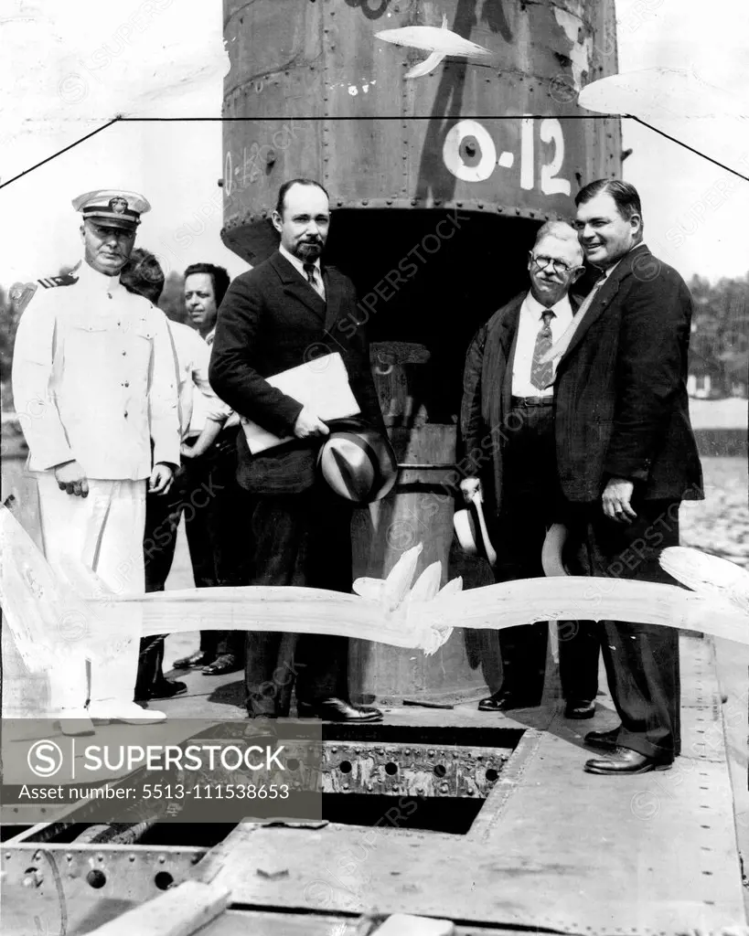 Noted Explorer Inspects Submarine for Undersea Polar Cruise: Sir George Hubert Wilkins, famous polar explorer, with submarine experts inspecting the old submarine 0-12, which is being remodeled for the Wilkins North pole undersea expedition. The craft was leased from the United States government and is to be renamed the "Nautilus". According to present plans the submarine will be ready next summer when the expedition is scheduled to start out for the Northern ice fields. In the group are, Capt. 