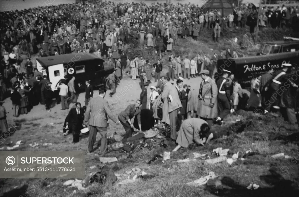 When Death From The Air Struck The Farnborough Hillside The grim scene on the hillside where the spectators were killed and injured casualties lie on the ground as first and is given. In background is an ambulance and a crowd which seams bewildered and stunned. Twenty persons - pilot John Derry and a passenger and 18 spectators were killed and 35 spectators were injured when the No. 1 prototype of the semi-secret De Havilland 110 all-weather jet fighter blew up at the Farnborough (Hampshire) air