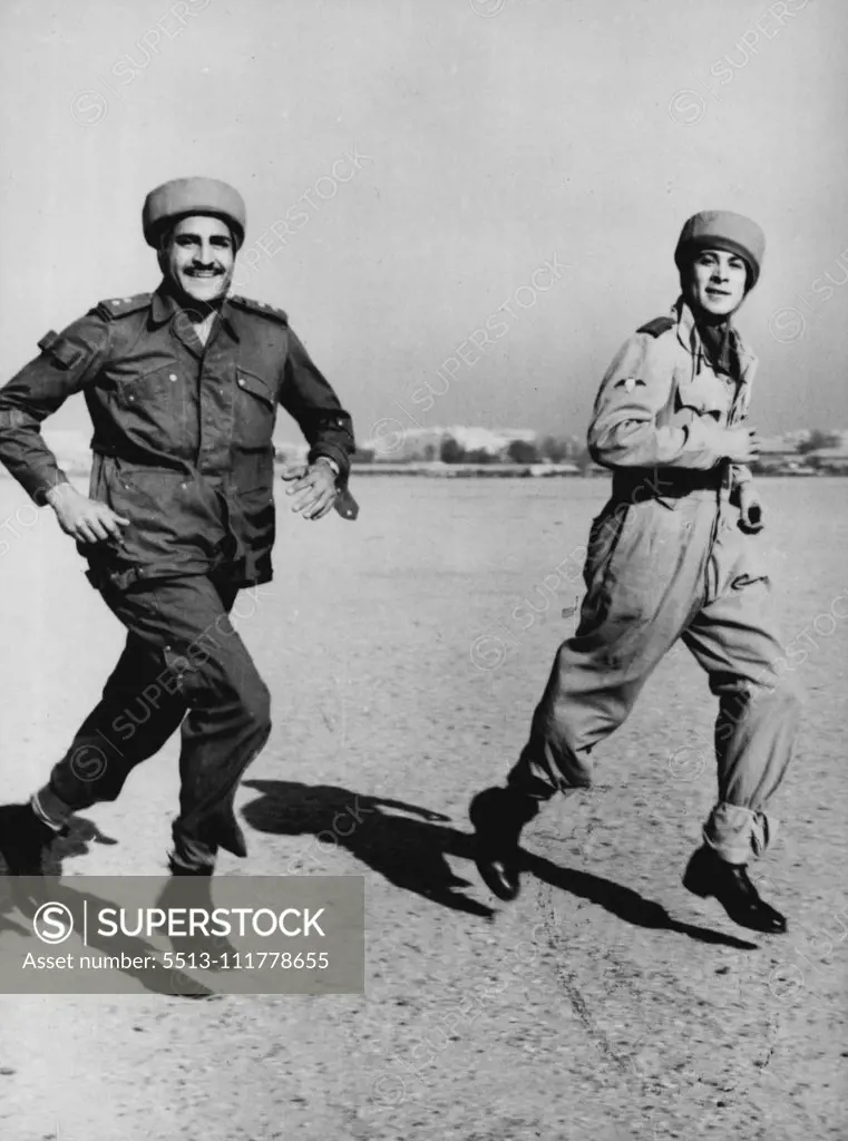 Egyptian Paratroopers Stage First Mandeuvers Captain Steimel (right, first name not available), German Instructor, runs to the waiting aircraft with an Egyptian paratrooper, during the first manoeuvres of the newly created Egyptian paratroop unit, November 29th. A Dakota aircraft of the Egyptian Royal Air Force took off from the Almaza Military Airport, with four Egyptian parachutists during the manoeuvres and later the parachutists baled out over a field. German experts who for several months h