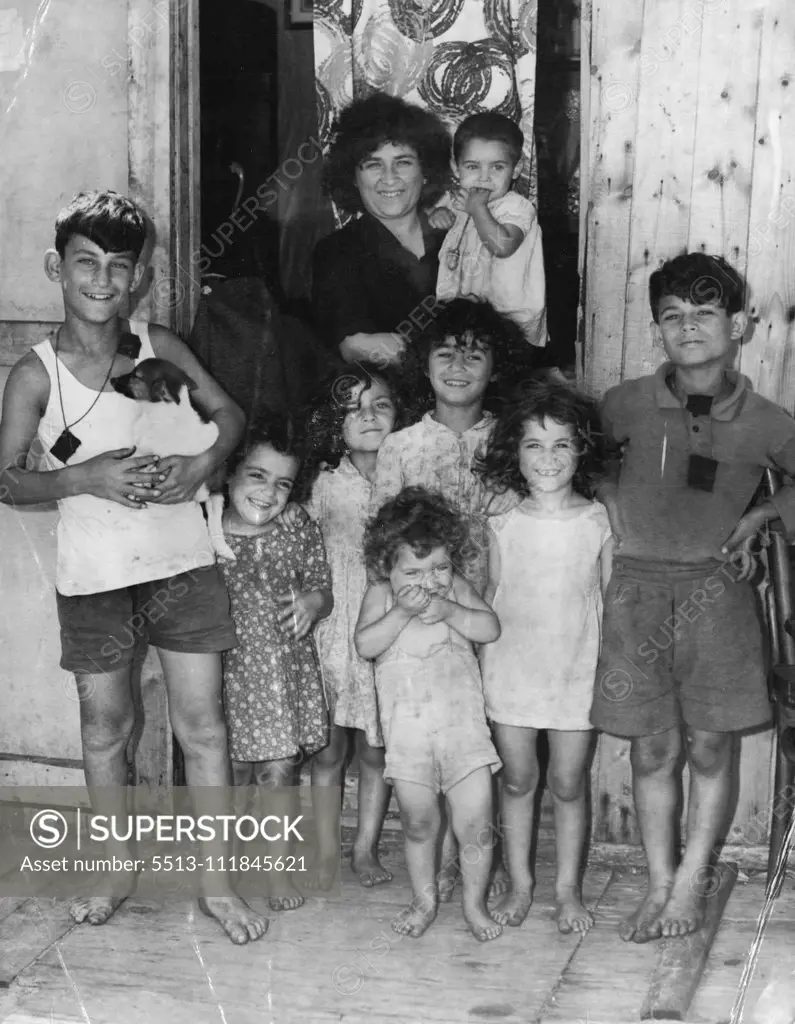 Mrs. Joseph Abela, who arrived with her husband from Malta 1½ months ago, stand with her eight children outside their iron and timber shack at Yarra Bay yesterday. March 12, 1952. (Photo by Wilmot/Fairfax Media).;Mrs. Joseph Abela, who arrived with her husband from Malta 1½ months ago, stand with her eight children outside their iron and timber shack at Yarra Bay yesterday.