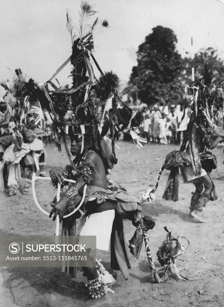 ia Dances For The Queen -- Bedecked with flowers, flags, ribbons and ankle bells and with towering headdress and flowing 'tail', a native dancer performs for the Queen during her visit to Port Harcourt on her ian tour. February 23, 1955. (Photo by Reuterphoto).;ia Dances For The Queen -- Bedecked with flowers, flags, ribbons and ankle bells and with towering headdress and flowing 'tail', a native dancer performs for the Queen during her visit to Port Harcourt on her ian tour.