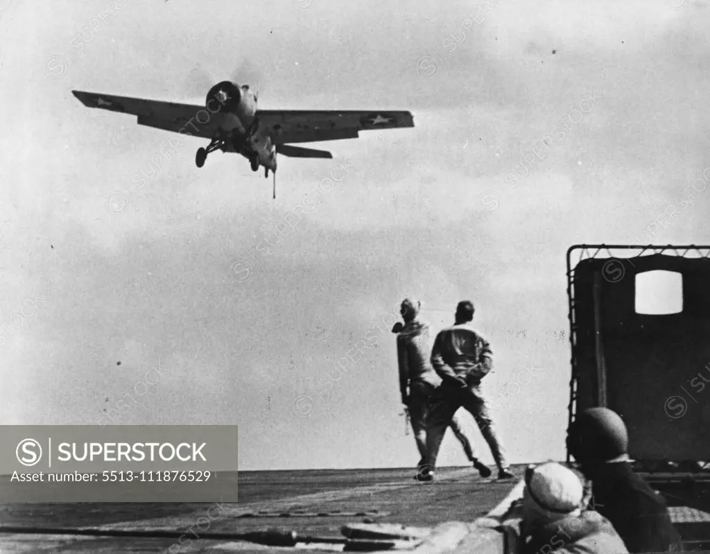 U.S. Navy Fighter Plane "Comes In" For Carrier Landing -- On the flight deck of a United States Navy aircraft carrier bound for Africa, a signal officer waves directions to be pilot of a fighter plane as the aircraft swoops low preparatory to landing. February 22, 1942. (Photo by Interphoto News Pictures, Inc.).  ;U.S. Navy Fighter Plane "Comes In" For Carrier Landing -- On the flight deck of a United States Navy aircraft carrier bound for Africa, a signal officer waves directions to be pilot o