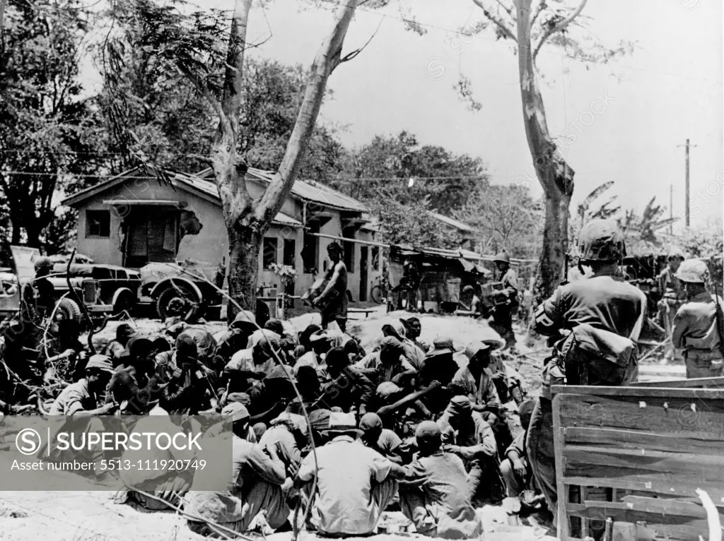 Japanese prisoners huddled together and guarded by Marine forces in Charon-Kanoa, Saipan, a few hours after the invasion began. July 06, 1944. (Photo by U. S. Coast Guard Photo)