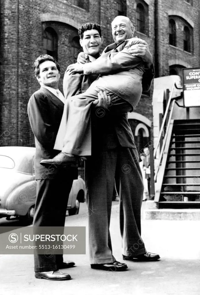 South Africa's Giant Boxer Arrives In England. Jack Solomons, the well known boxing promoter, is picked up in greeting by Potgieter after arriving at Victoria Stn, London. On left is Freddie Mills, the former British light-heavyweight champion. Ewart Potgieter, the giant South African heavyweight boxer, has arrived in London, to commence training for his contest against Botticeli, of Italy, at the White City in September. Potgieter stands 7 feet 2 inches in height and weighs 22½ stone. August 02, 1955.