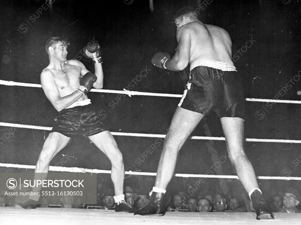 Ewart Potgieter (right) towers over 6ft 2in Fred McCoy as he bears down on him in their Durban fight. Making his ring debut, Potgieter, weighing 318¼lb an standing 7ft 2in high, sent McCoy out of the ring for the full count within 30 seconds of the opening bell. Potgieter dwarfs his 13st 21b opponent Fred McCoy as he advances to launch a 30-second knockout attack. December 01, 1954.