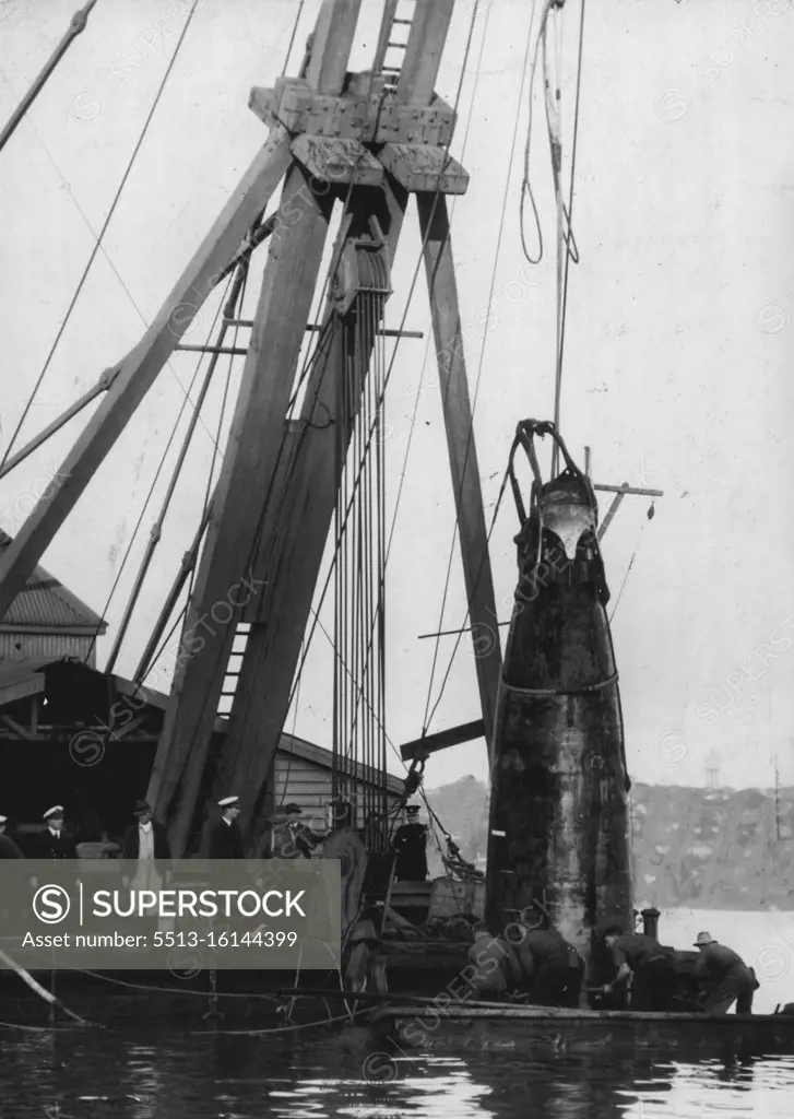 ***** of the submarine, with a torpedo protruding from a tube, ***** the midget vessel was drawn slear. Men are seen attaching ***** hawsers lower down the shell. June 10, 1942. 