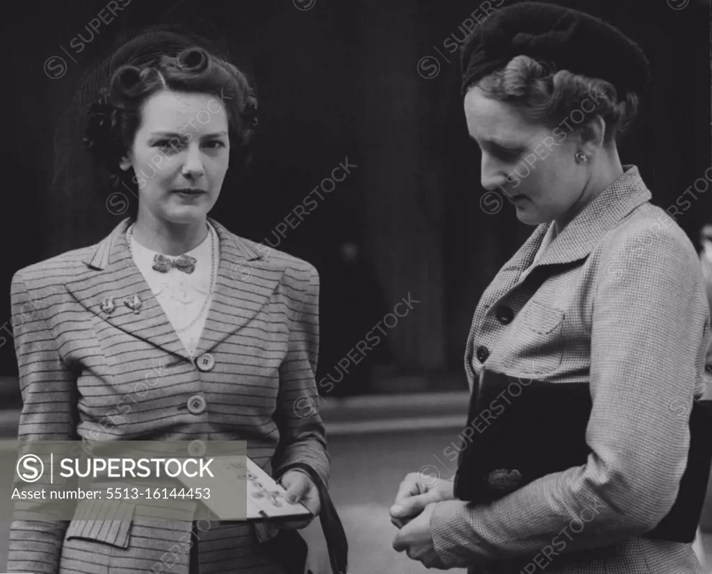 At a recent Investiture held by the King -- Mrs. Collyns (left) with the DFC awarded to her late husband, F/LT. Basil Collyns, of the Royal New Zealand Air Force, after receiving the decoration form the King. On right decoration from the King. On right is her mother in-law, Mrs. Uollyns. March 26, 1945. 