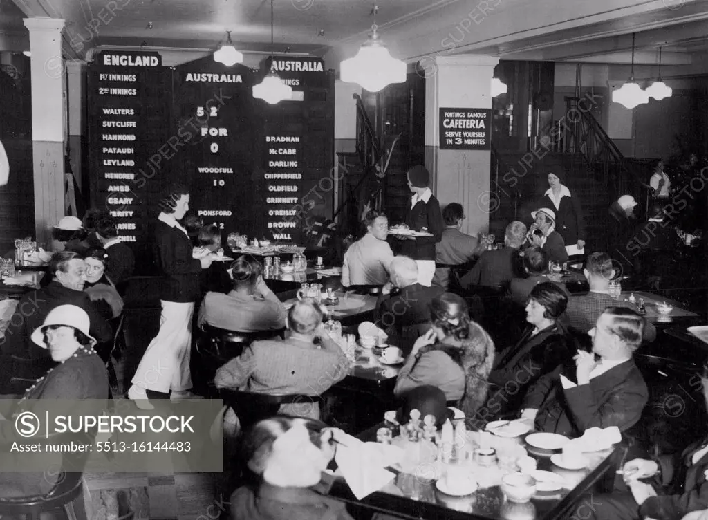 Lunch Scores -- Diners watching the scoreboard in operation today. Note waitresses in white trousers. A Cricket scoreboard has been created in the restaurant of Messrs. Pontings' Stores, so that the diners in London may watch the progress of the test match, run by run. Watch run is recorded immediately it is scored. June 8, 1934. (Photo by London News Agency Photos Ltd.).