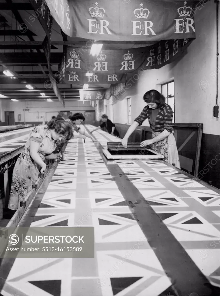Flags By The Mile - For Coronation. Union Jacks that will give colour to Coronation day celebrations are finished by workers at a Rochford, Essex, factory. From the roof hang other banners, bearing the Crown and cipher. At work on the table are - left - Shipley Wellington (Rochford); and Brenda McGrath (Southend). At right of table - Jean Cushen (Eastwood) and Rita McGrath (Southend). January 12, 1953. (Photo by Reuterphoto).