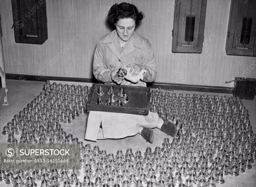Miniature Bells For Coronation Souvenirs. Miss Doreen Smith, aged 22, of South Norwood, surrounded by hundreds of the miniature bells, which she is cleaning and inspecting. At the foundry of Messrs. Gillett & Johnston, Ltd., in Croydon, miniature bells are being cast from metal obtained from bells which were cast in the time of Queen Elizabeth I. They are perfect replicas and have a Coronation inscription. February 17, 1953. (Photo by Fox Photos).