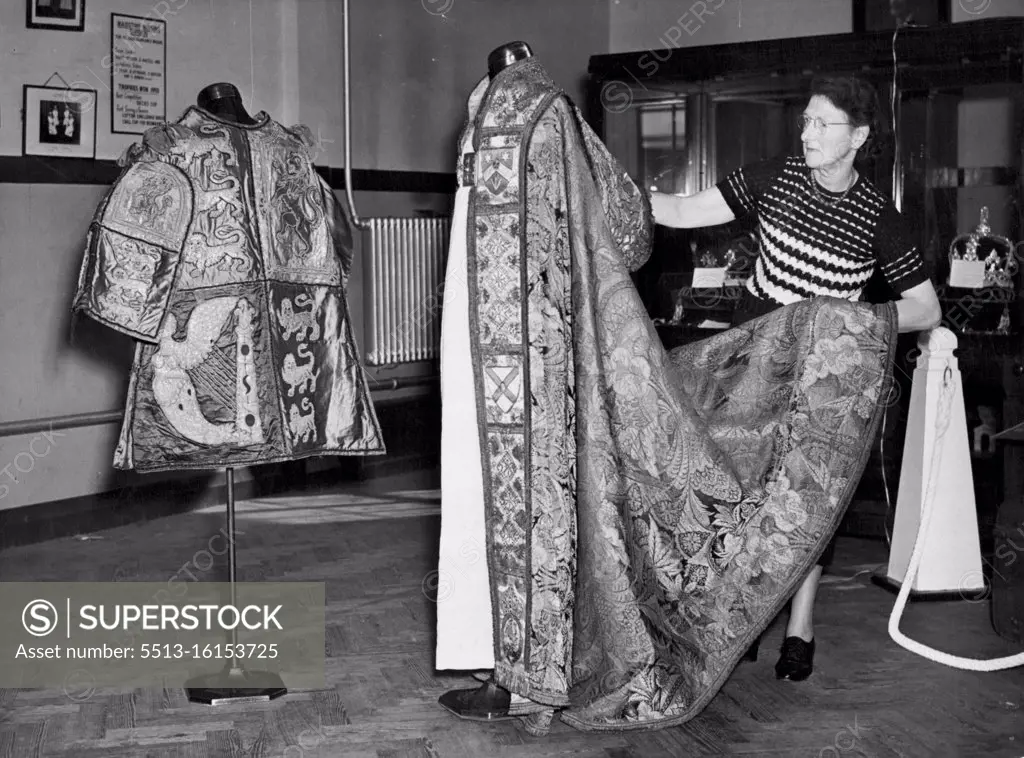 Kent Sees Coronation Robes and Crown Jewels Replicas Mrs. M.M. Beaumont of Sittingbourne, wife of the Secretary to St. Johns Order and Area Commander prepares the Coronation cope of the the Archbishop of Canterbury. On left is the tabard of Sir Gerald Woods Wollaston, KCB, KCVC, Norroy and Ulster King at Arms. Viscountess Allerby today opened an exhibition of Coronation robes and or replicas of the Crown jewels at Dunk memorial Hall, Maidstone, Kent, held by the council of the Order of St. John to raise funds for their cadets. The exhibition will be held also at Canterbury and Tunbridge wells. October 04, 1952. (Photo by Fox Photos).
