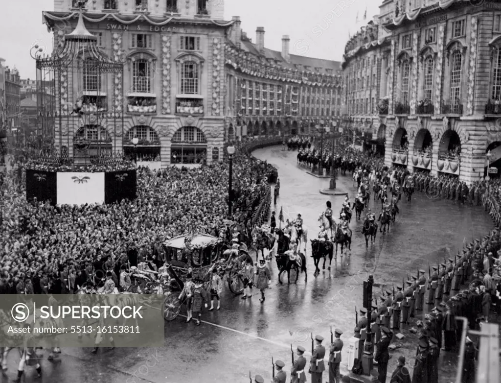 While Eros Watches The Procession Passes By -- Across a rain swept Piccadilly Circus the golden coach of Queen Elizabeth II passes while behind up the length of rose decorated Regent Street the procession follows in its journey back to the Palace from Westminster Abbey. On the left Eros in special protective cage can be seen. June 02, 1953. (Photo by Daily Express Picture).