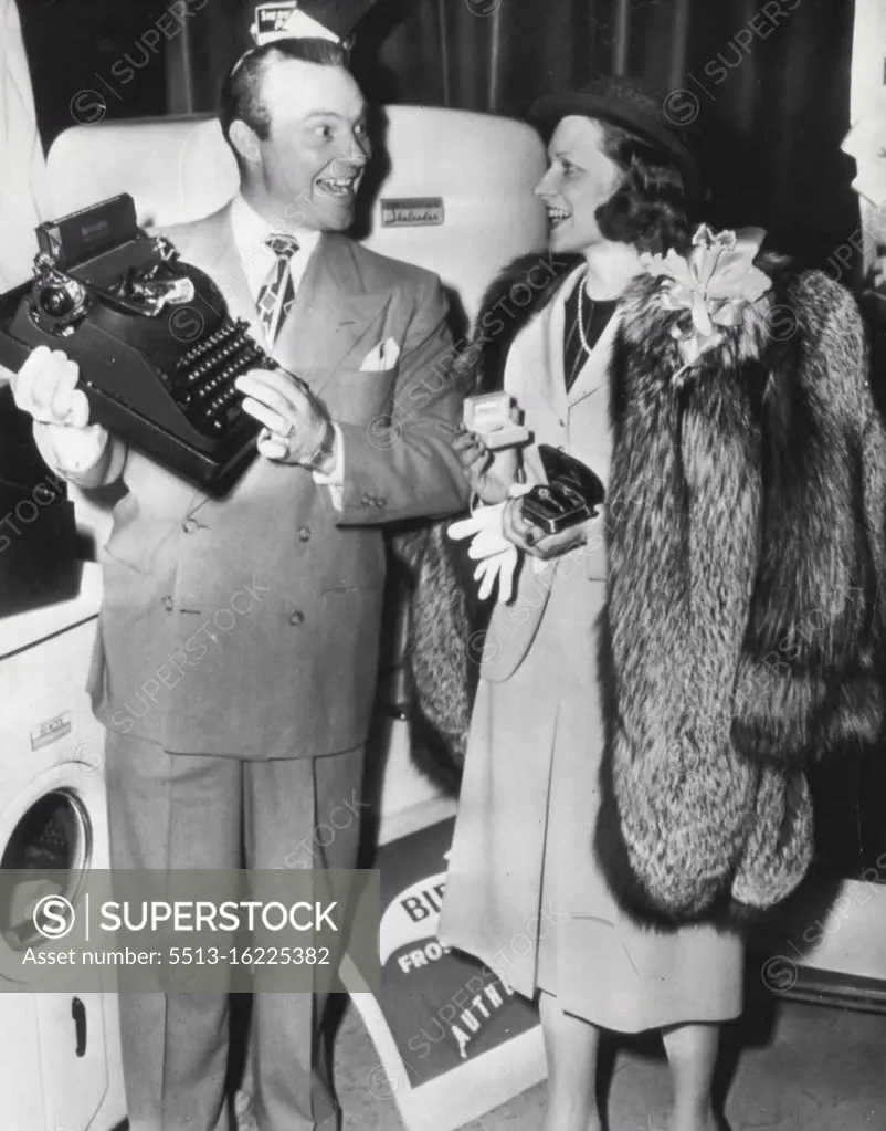 Hush Money -- Mrs. William McCormic, Lockhaven, Pa., housewife who identified ex-film actress Clara Bow as "Mrs. Hush" to win a radio contest, receives some of the $17, 000 worth of prizes from program director Ralph Edwards. Here today. She holds a diamond and rugy wristwatchk, a diamond ring and wears a fur coat. In background is a washing machine and a refrigerator. March 22, 1947. (Photo by AP Wirephoto).