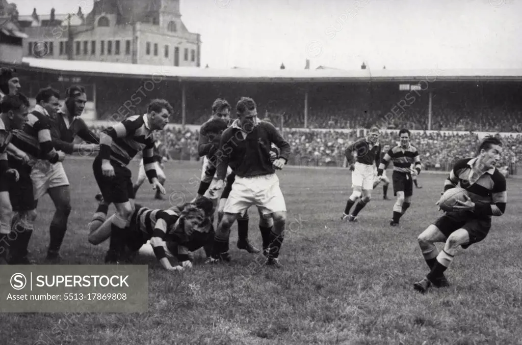 South Africans Win At Cardiff -- J.D. O'Brien (Cardiff - on ground in skull-cap) gets the ball to R. Willis who starts a three-quarter movement. After a stern battle the South African Springboks won their match against Cardiff- at Cardiff - by 11 points to 9. October 20, 1951. (Photo by Sport and General Press Agency, Limited).