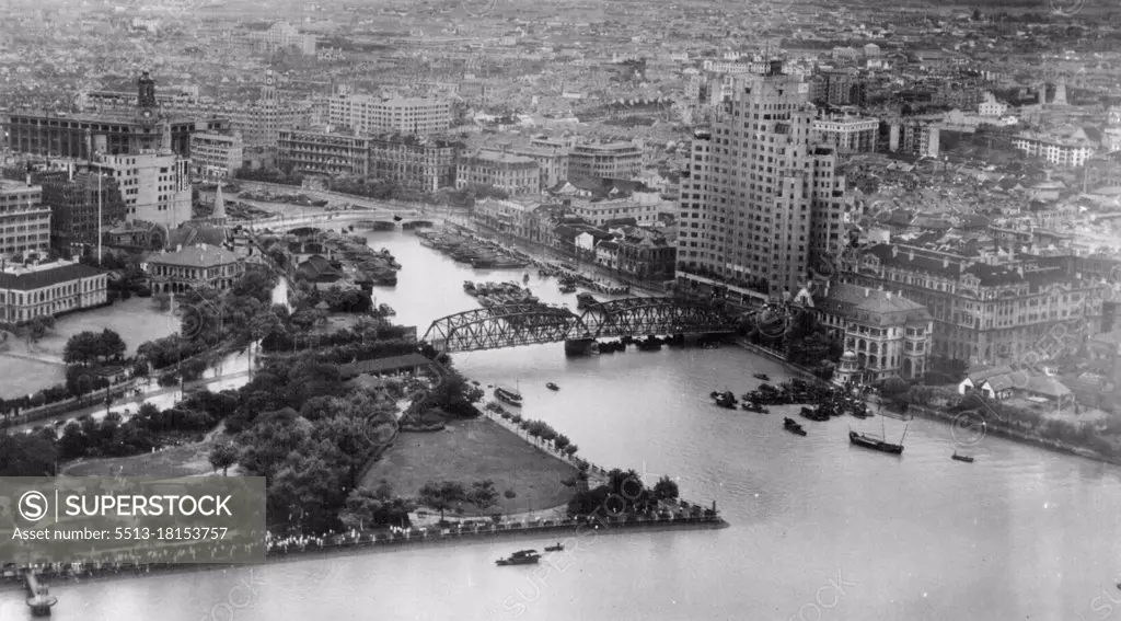 Shanghai.On the right bank of Soochow Creek is seen the Astor Hotel, on the left bank behind the park is the old British Consulate. Many people are seen along waters edge viewing Navy TBM overhead. October 15, 1945. (Photo by Official U.S. Navy Photo).