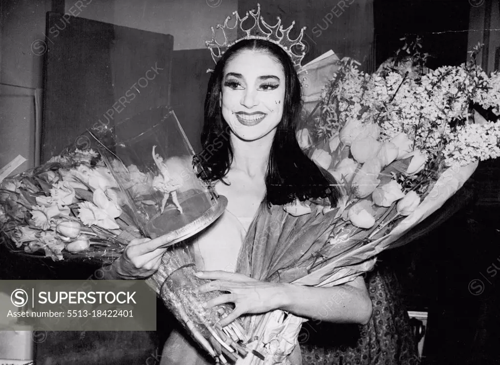 Partner For Don Quixote - 12 Encores For British Star -- Margot Fonteyn returning with an armful of flowers and a ballerina doll, to her dressing room at the Royal Opera House, Covent Garden, London. She danced as Dulcinea in the first performances of the ballet "Don Quixote". Margot too 12 curtain calls. For three of them the stars were joined by Ninette de Valois, "Don Quixote" is her first ballet for seven years. February 21, 1950. (Photo by Paul Popper Ltd.)