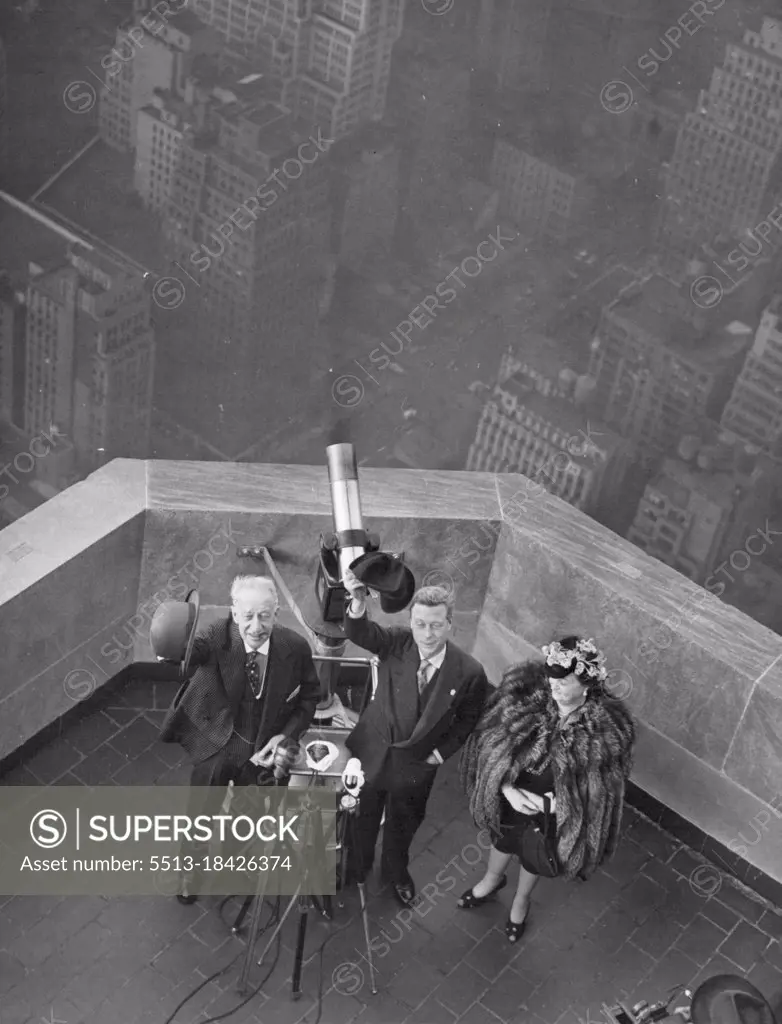 Above the sidewalks of New York -- The Duke of Windsor (center) waves his hat while being shown the empire state building and its view of New York Oct. 21 by former Governor Alfred E. Smith and his wife, That's a telescope behind them as they stand on an observation platform near the Top of the Building. October 21, 1941. (Photo by Associated Press Photo).