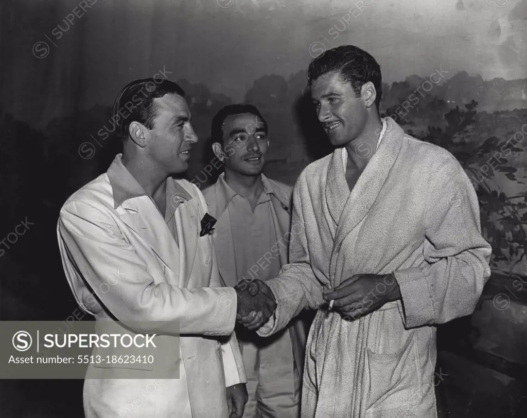 A star of the roped square meets a star of the silver screen -- Ken Overlin, American boxer, who will fight Fred Henneberry at the Stadium next Monday night, meets Errol Flynn, Australian movie actor, during a visit to Hollywood. Chris Durdie, Overlins' manager, looks on. May 26, 1938.