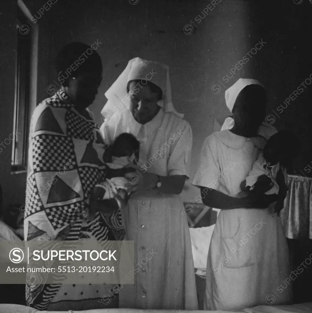 The Matron on her morning rounds stops at the maternity ward to see the twins. With her is Nurse Tepi, a mid-wife trained at the Zanzibar Hospital. The mother is the wife of a Zanzibar farmer. September 19, 1951. (Photo by British Official Photograph).