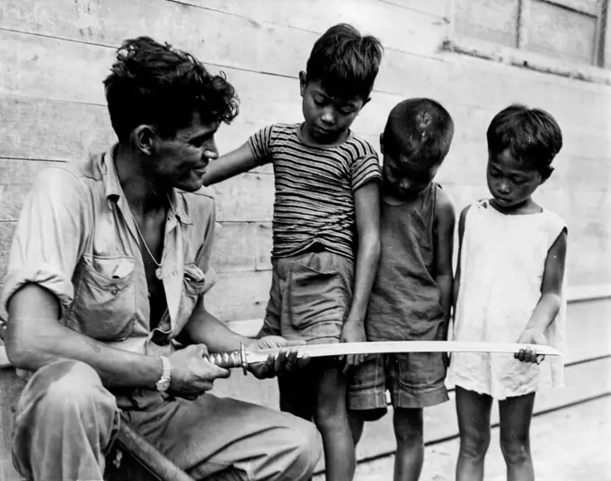 Hero Worship -- Filipino children solemnly inspect a Samurai sword that Private First Class Cornelius A. Lubo, Syracuse, New York, took from a Jap officer after slaying him and his sixteen-man patrol at Palo Bridge, Palo, Leyte Island. December 11, 1944. (Photo by USA Signal Corps Photo).