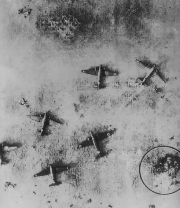 Tunis Air Field After British Raid -- This view of an air field at Tunis was made from a British reconnaissance plane Nov. 12, The day after at RAF raid on the field. Burned plane at lower right (circled) is identified as an Italian craft, Plane nearest it as another Italian ship with German markings, and the other five as German Junkers Troop Transports. December 13, 1942. (Photo by AP Wirephoto).