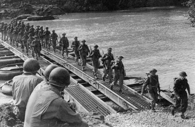 Crossing the River Volturno: Three American engineers watch British troops and transport crossing a Volturno Bridge. On October 13th, 1943, under cover of darkness the Fifth Army made its big assault on the River Volturno, one of the major barriers to advance on Rome - and crossed in force. October 31, 1943. (Photo by Fox Photos).